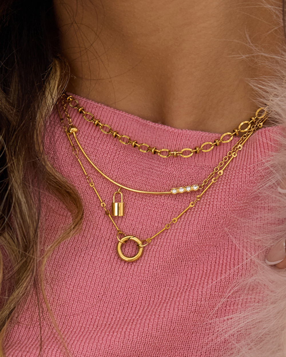 Gold chain necklaces on a person wearing a pink top