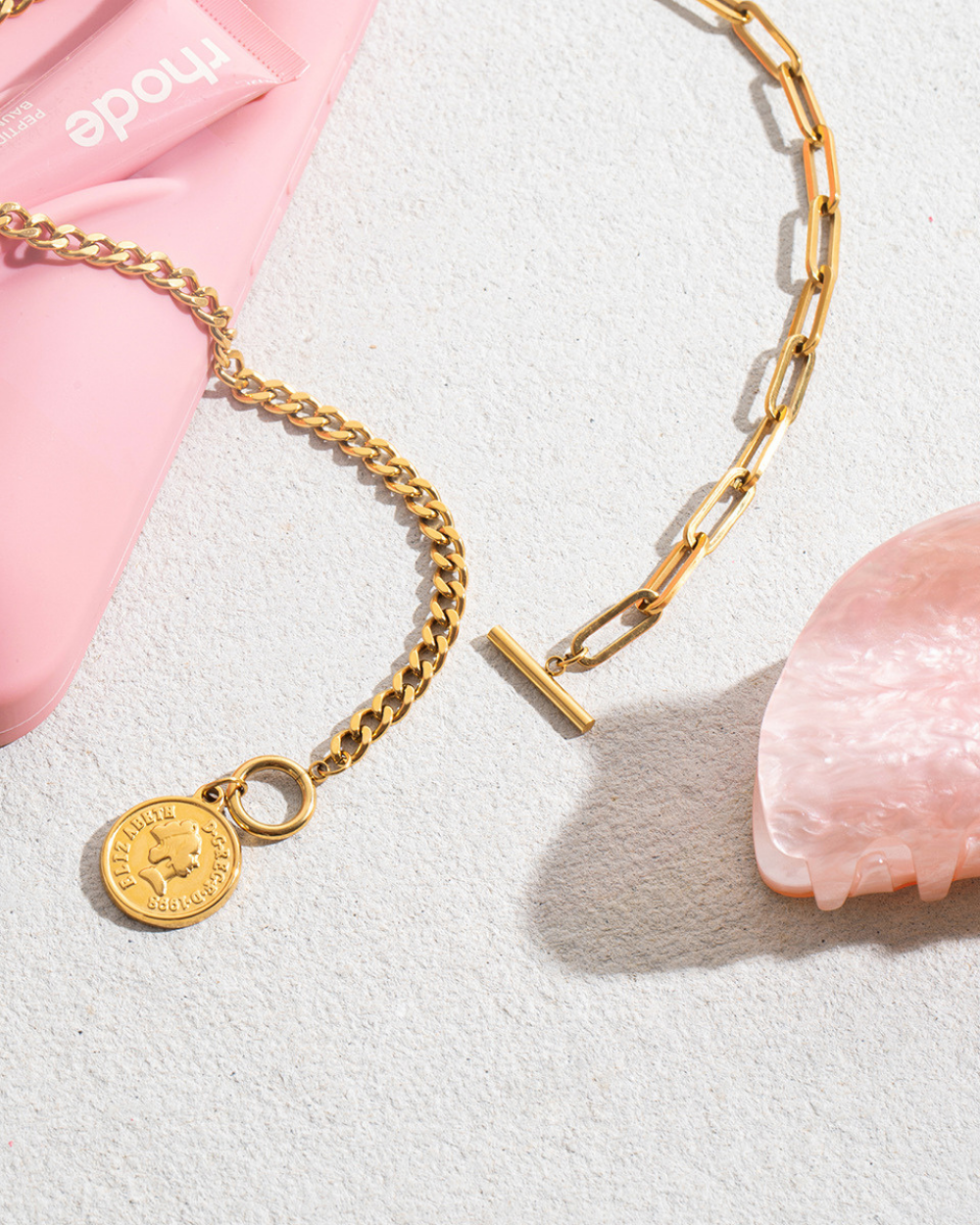Gold chain bracelet with a round charm on a light gray background