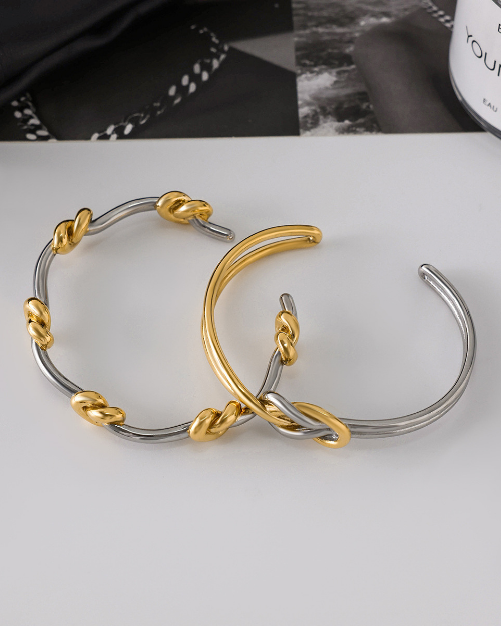 Pair of gold and silver hoop earrings on a white surface.