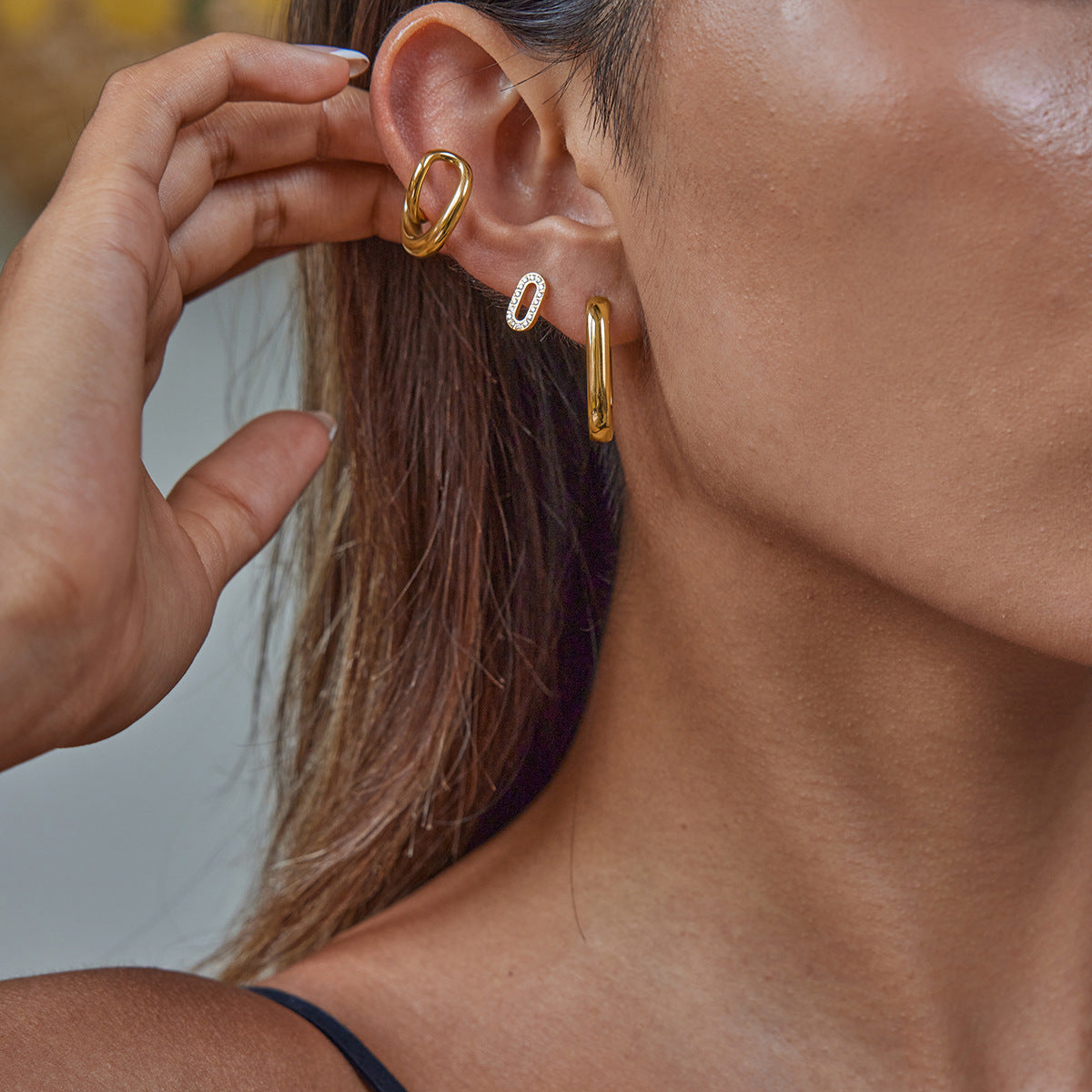 Model wearing stackable gold hoop earrings in multiple piercings
