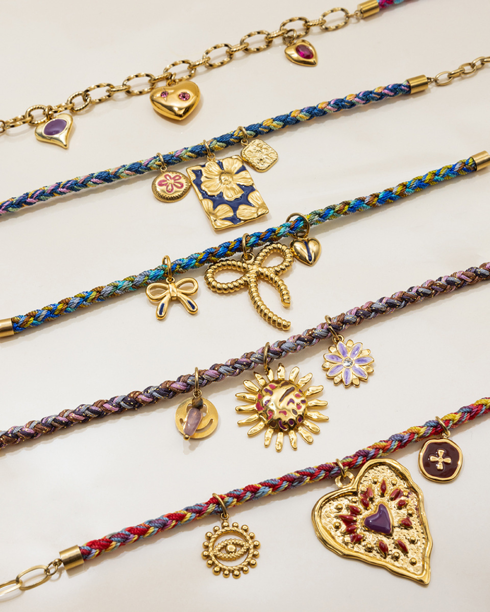 Colorful braided bracelets with various charms on a white background