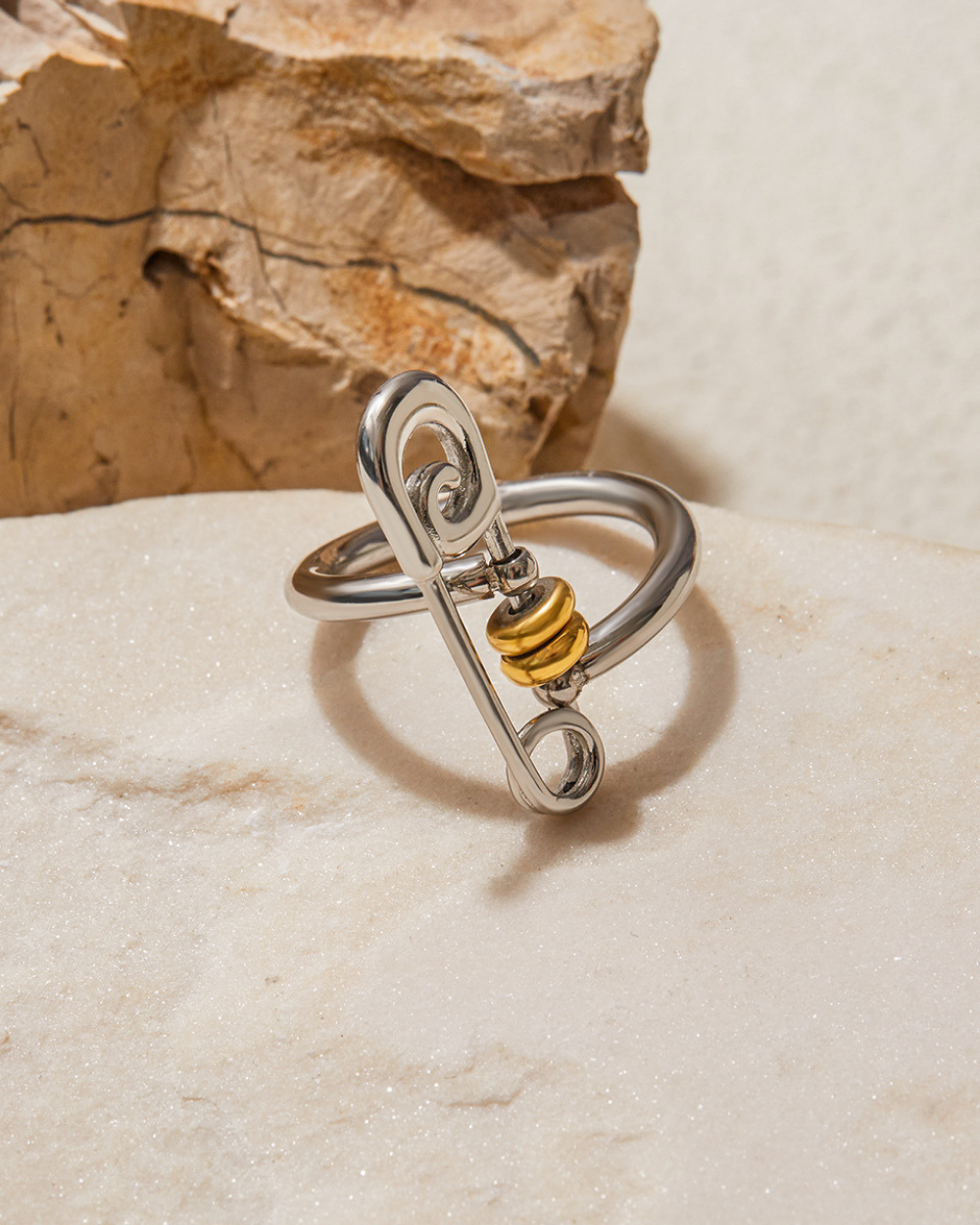 Silver ring with a gold accent on a stone surface