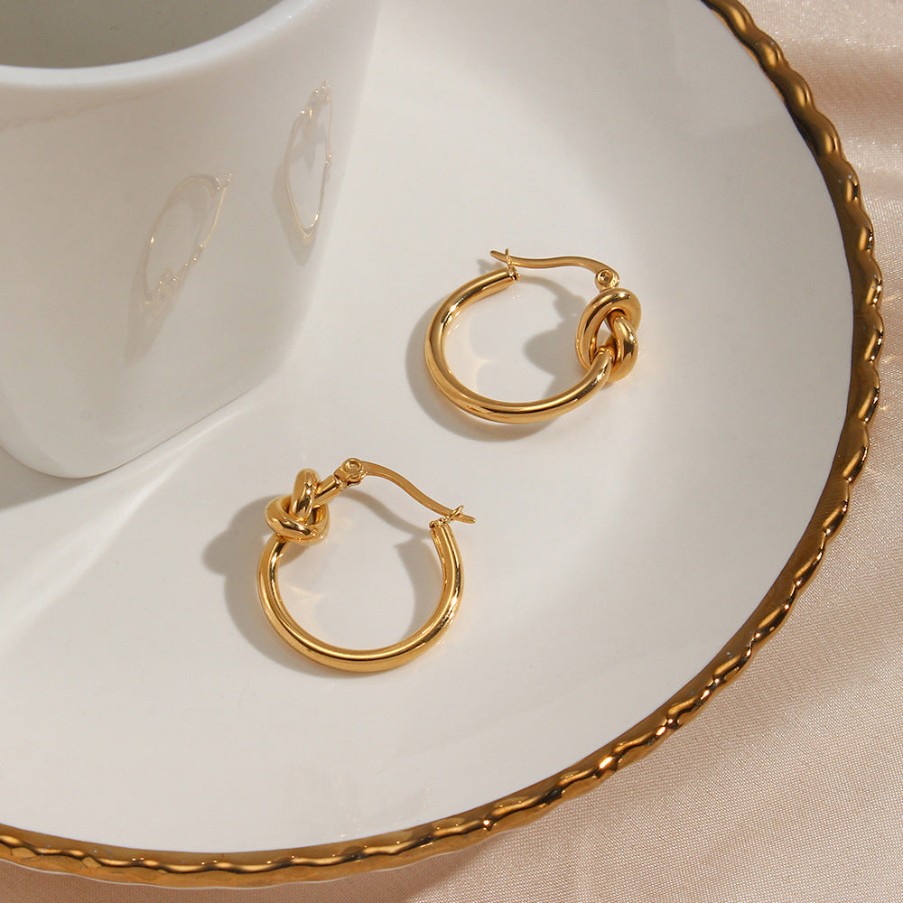 Flat-lay of knotted hoop earrings against a neutral linen background