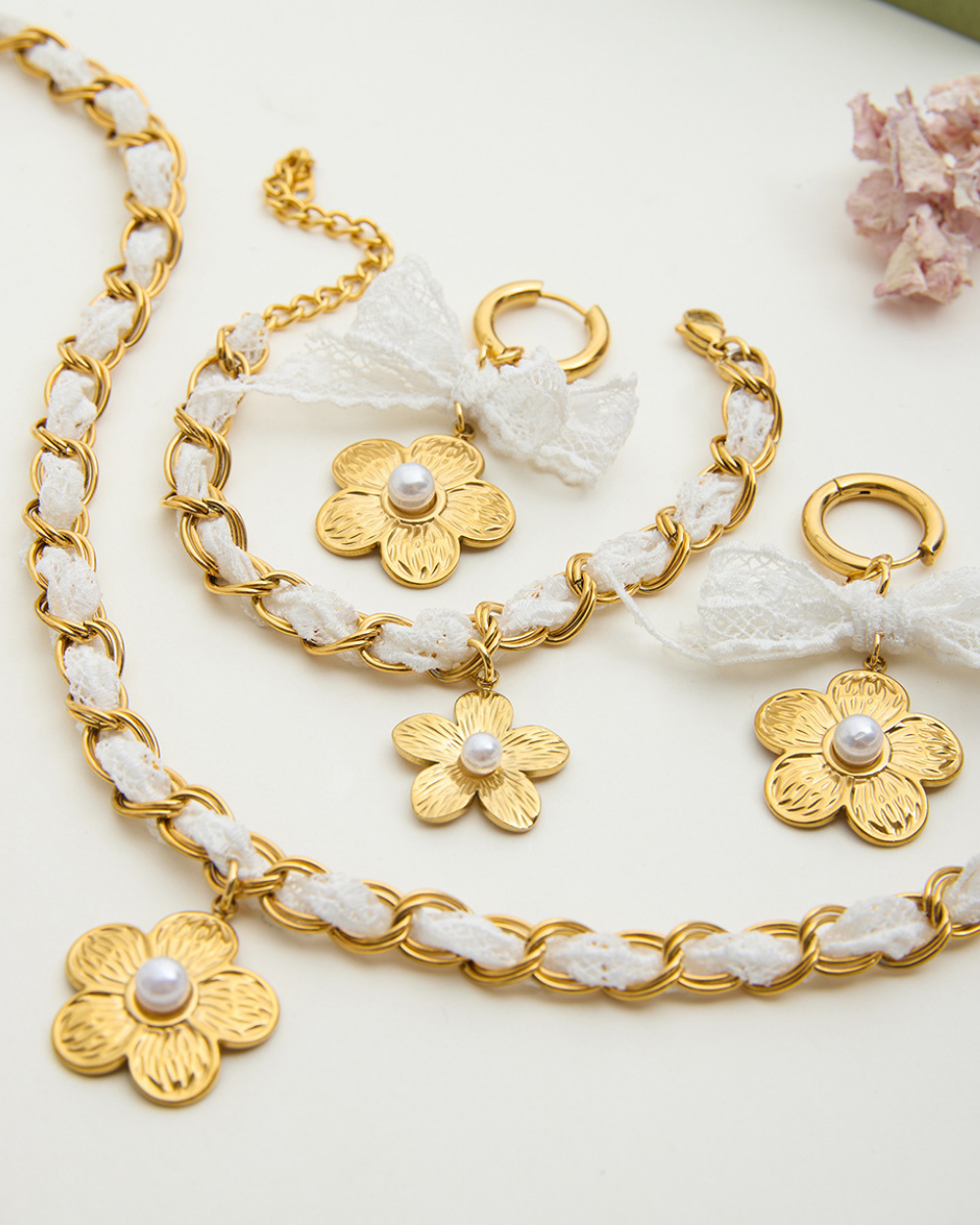 Gold jewelry set with floral designs and pearls on a white background