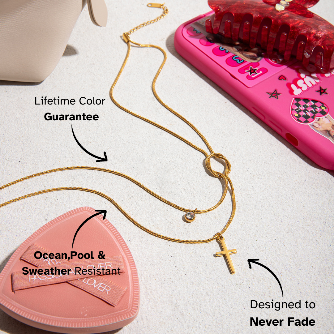 Gold necklace with a pink heart-shaped product and pink phone on a light surface