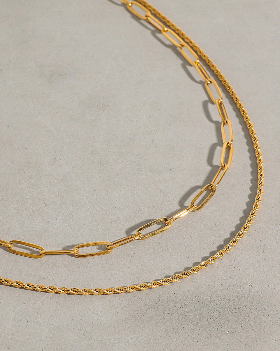 Two gold chains on a light gray background