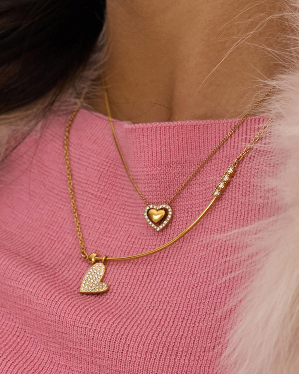 Gold necklaces with heart pendants on a pink sweater