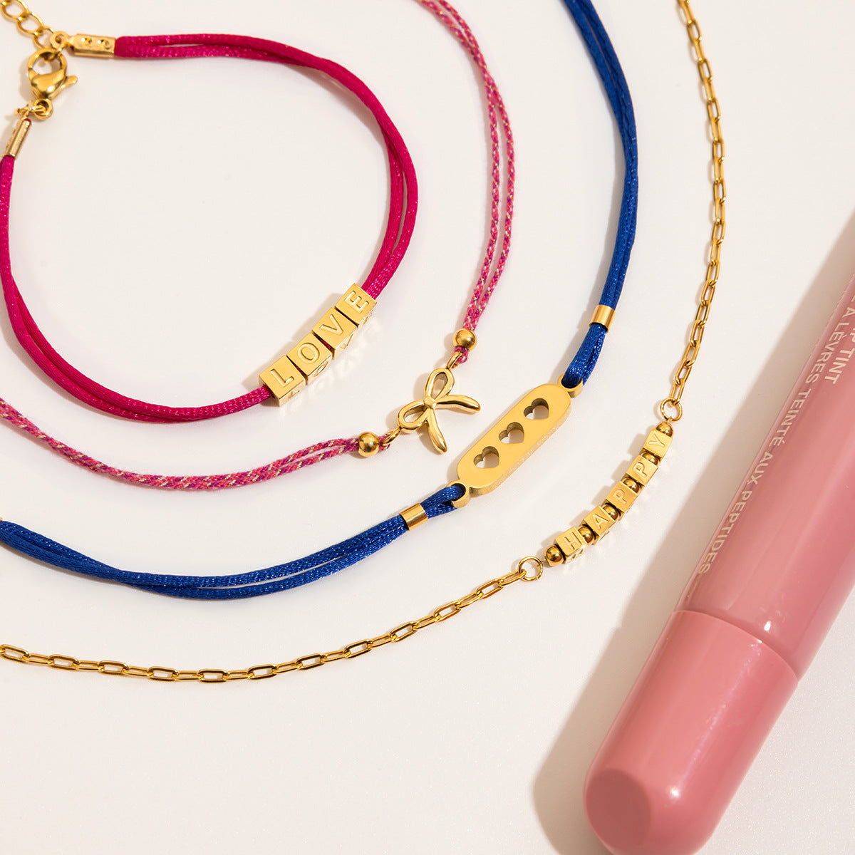 Jewelry set with pink, blue, and gold necklaces on a white background