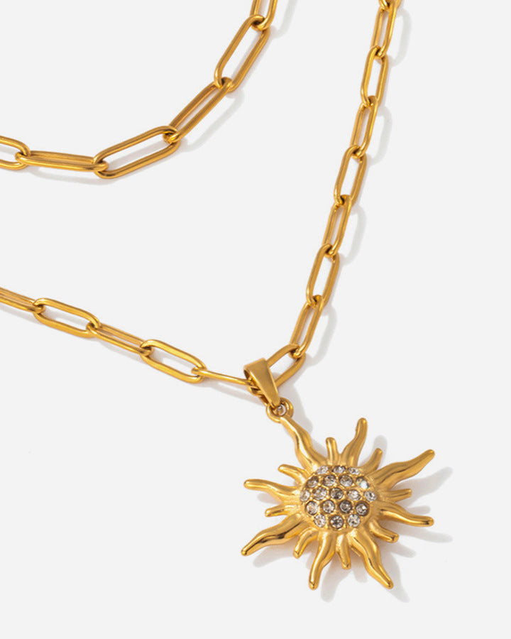 Gold chain necklace with a sun-shaped pendant on a white background