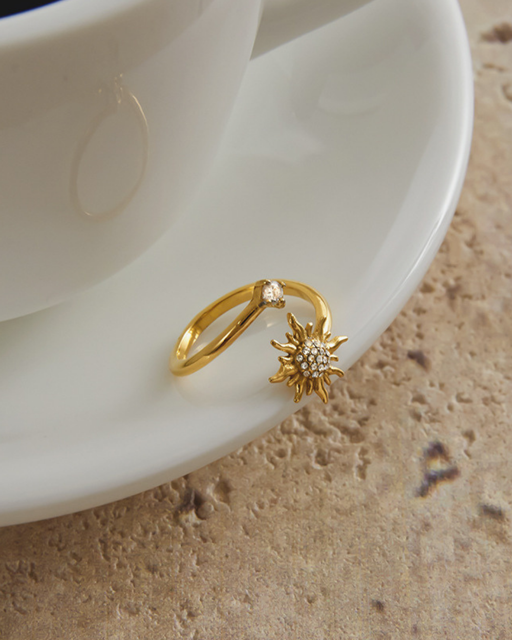 Gold ring with sun design on a white ceramic plate