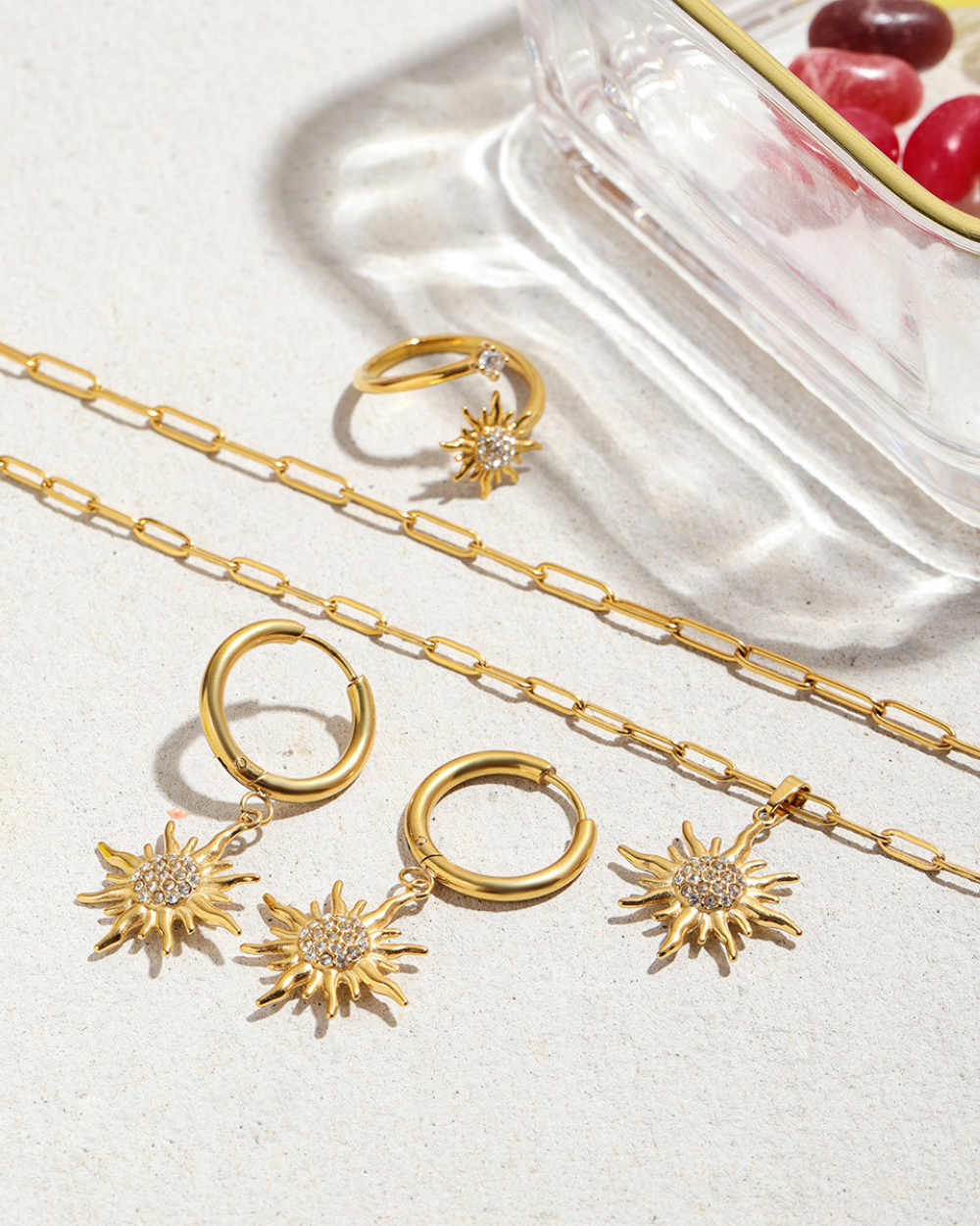 Gold jewelry set including necklaces, rings, and earrings on a light background.