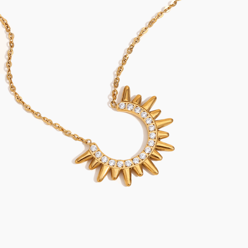 Gold necklace with a sun-shaped pendant on a white background
