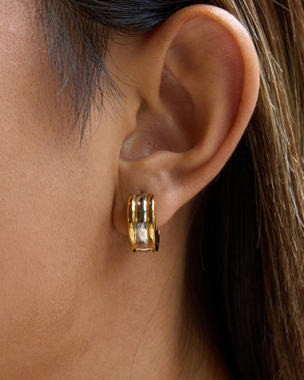 Close-up of an ear wearing a gold hoop earring.