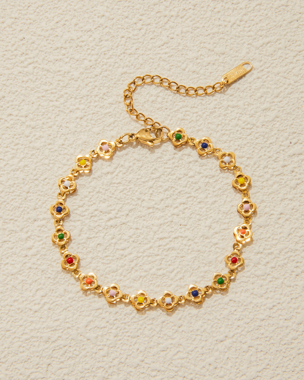 Gold bracelet with colorful gemstones on a light gray background