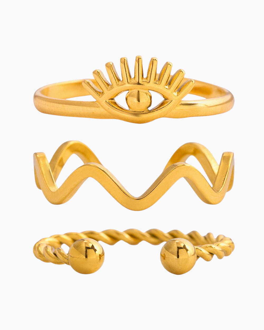 White background product photo of a 3-piece gold ring set: evil eye ring with sunburst lashes, wavy zigzag band, and twisted open ring with ball ends.