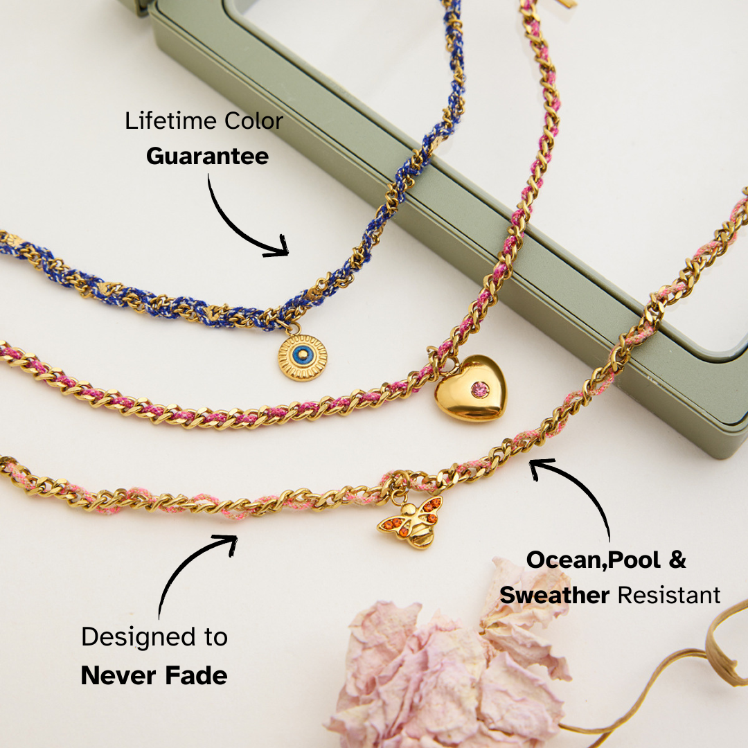 Gold bracelets with heart charm and blue and pink braided design on a white background