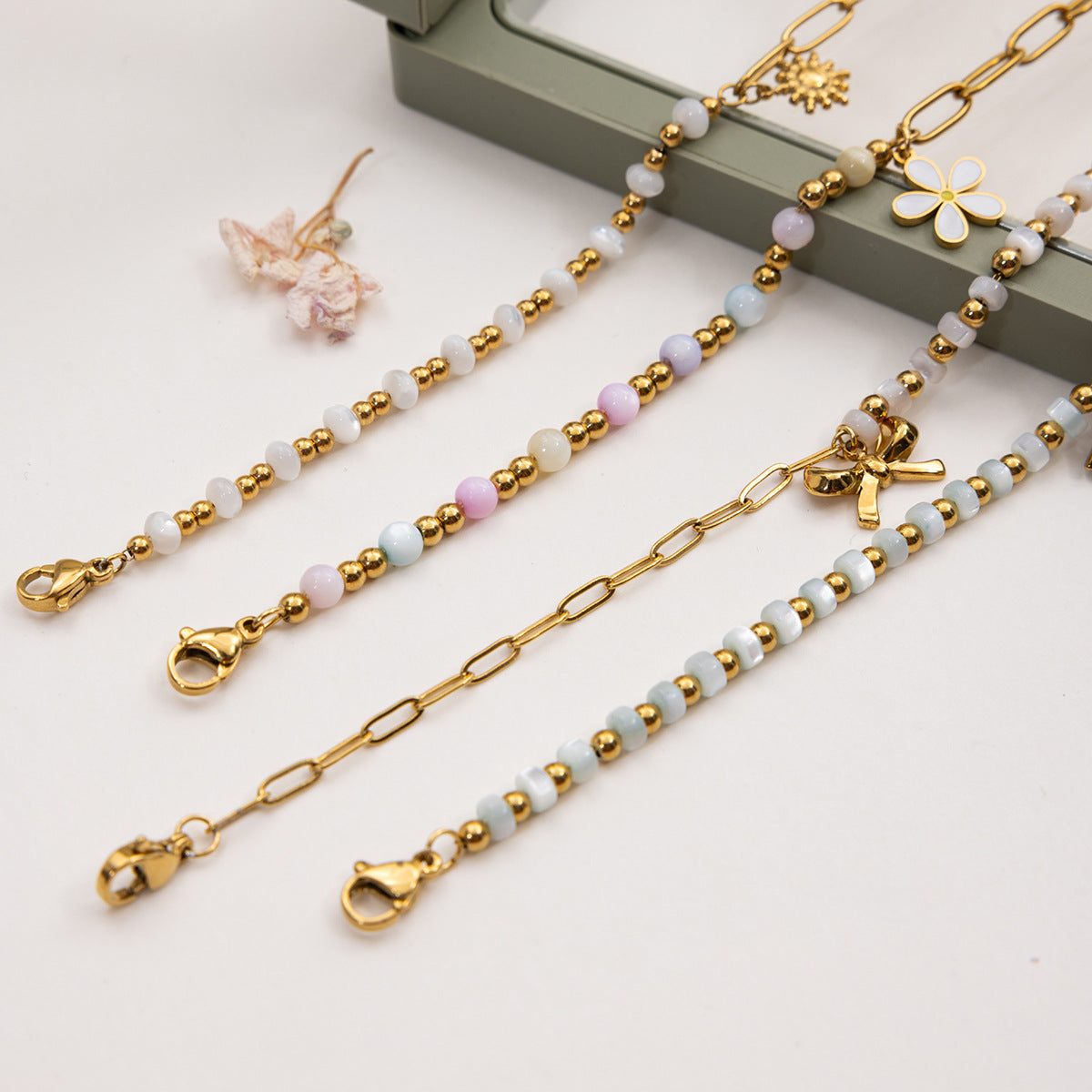 Gold and beaded jewelry on a white surface with a neutral background