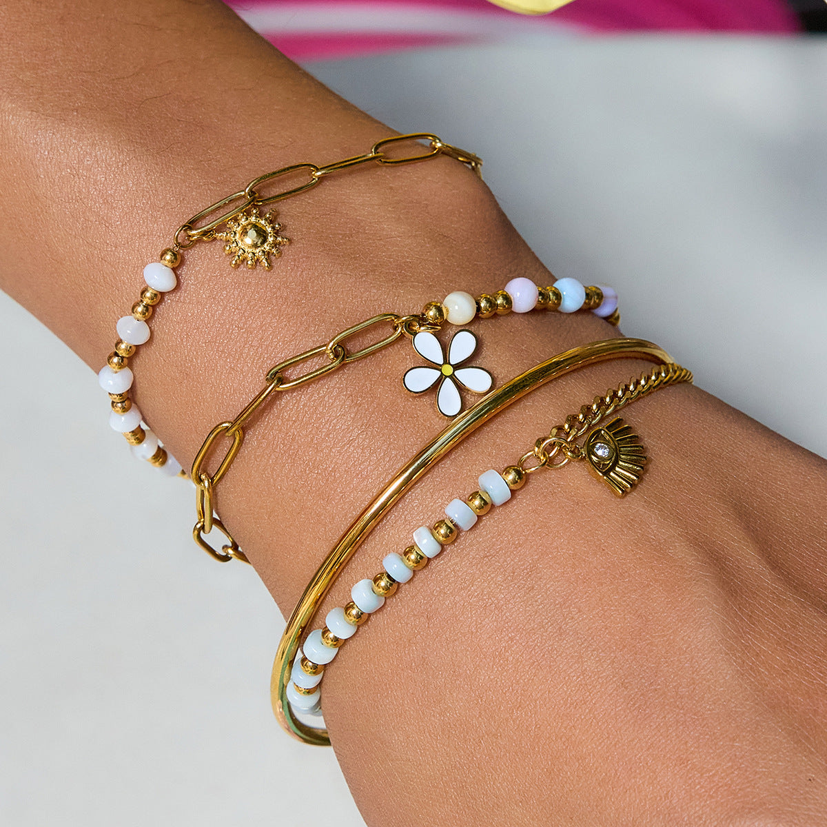 Gold and beaded anklets on a person's ankle against a neutral background