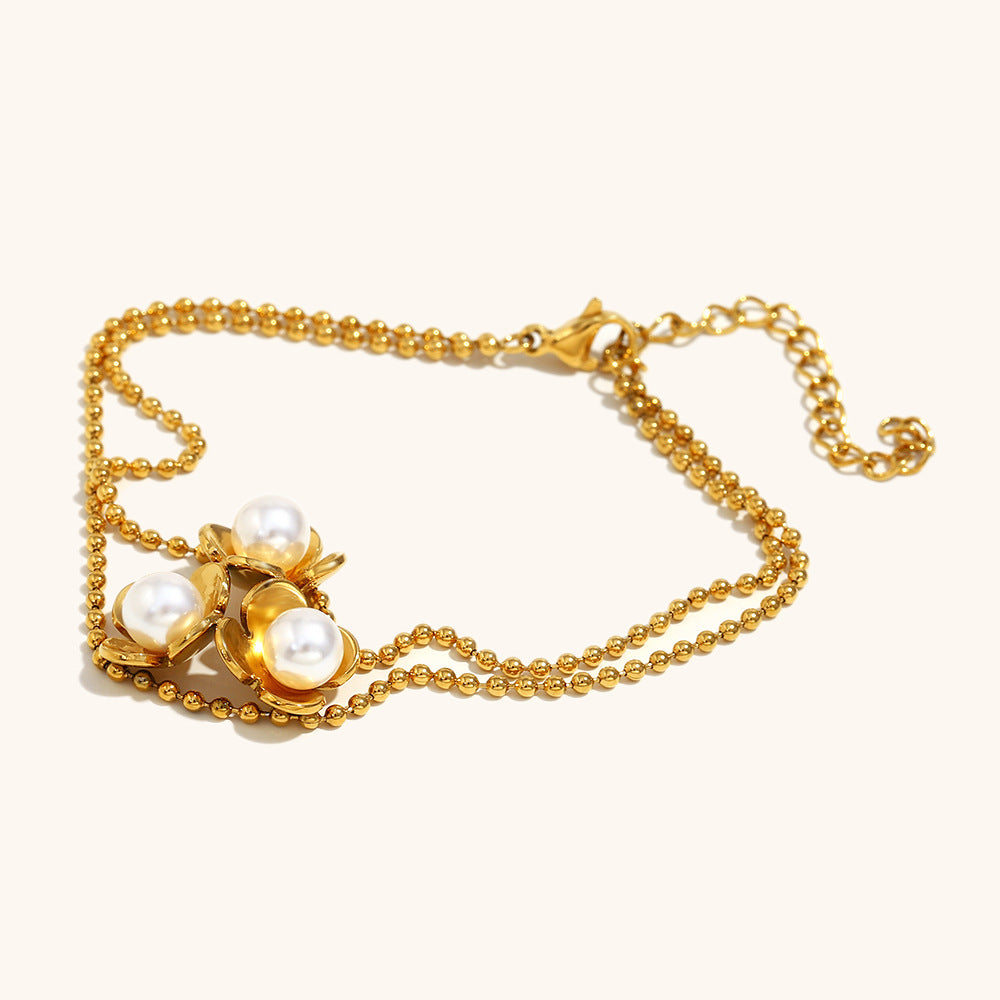 Close-up of pearl flower charm bracelet with gold bead chain
