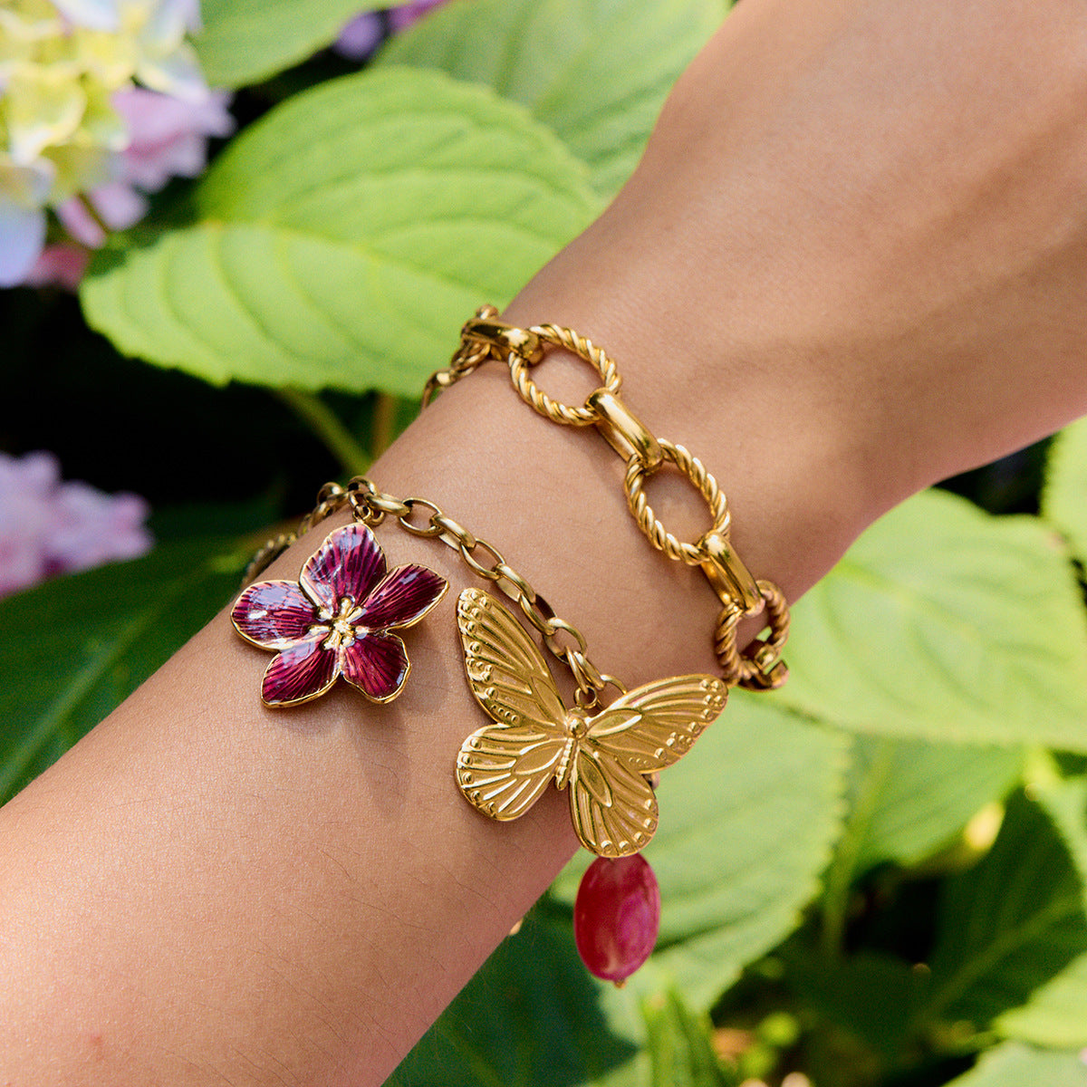Woman wearing butterfly charm bracelet with floral enamel pendant outdoors