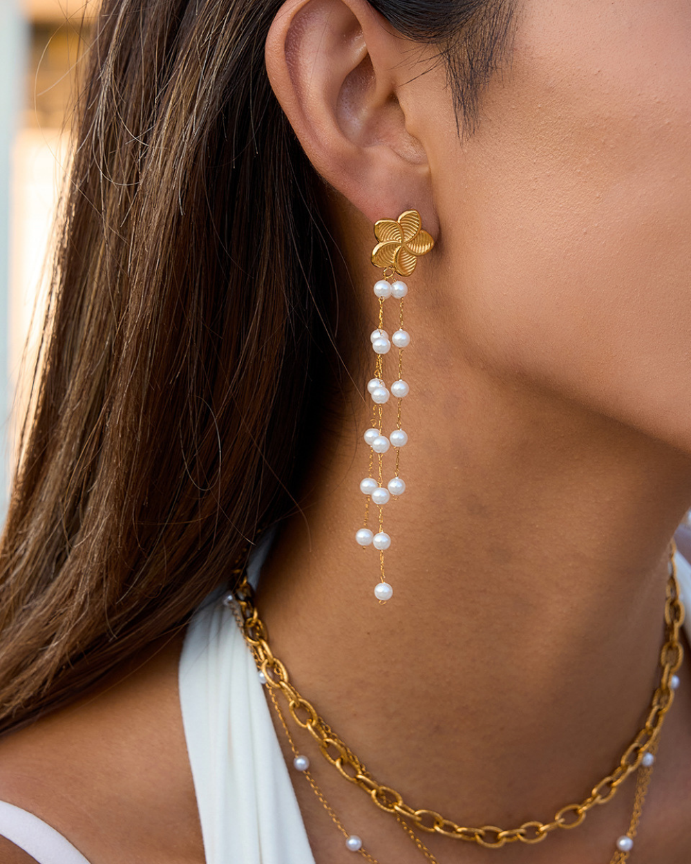 Gold earring with pearl drops worn by a person