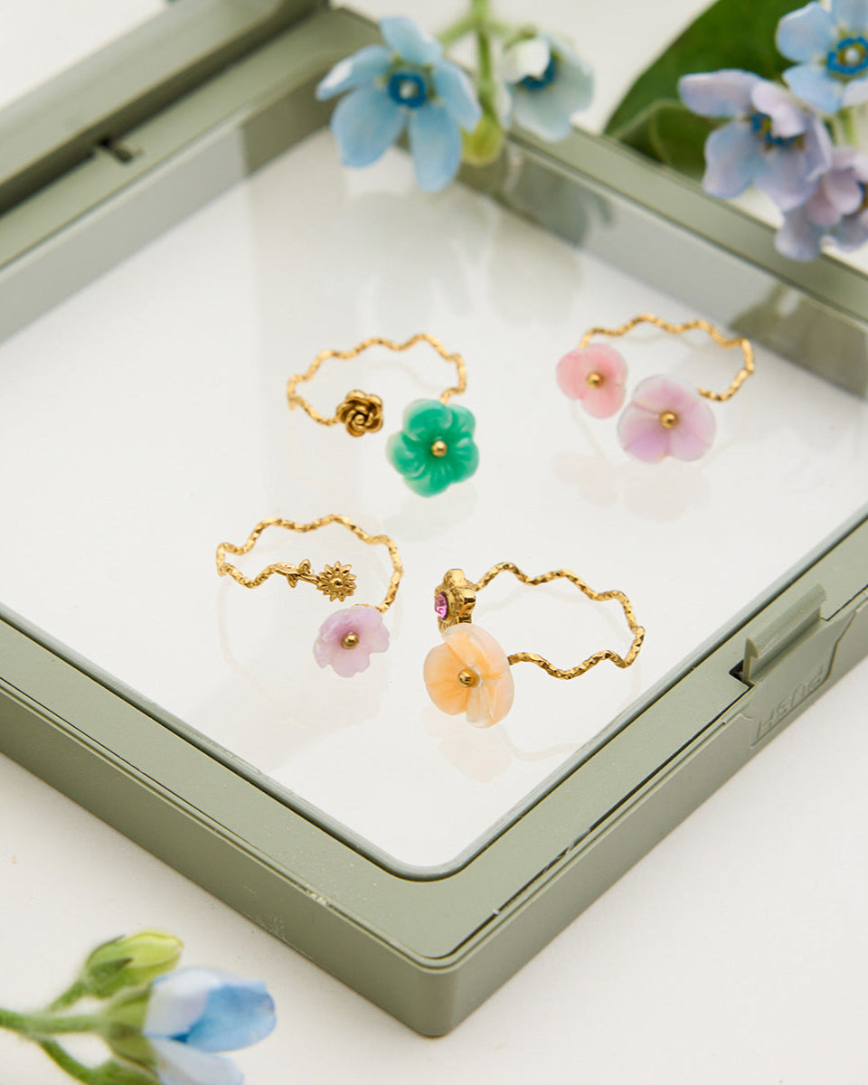 Set of floral earrings in a jewelry box with flowers around