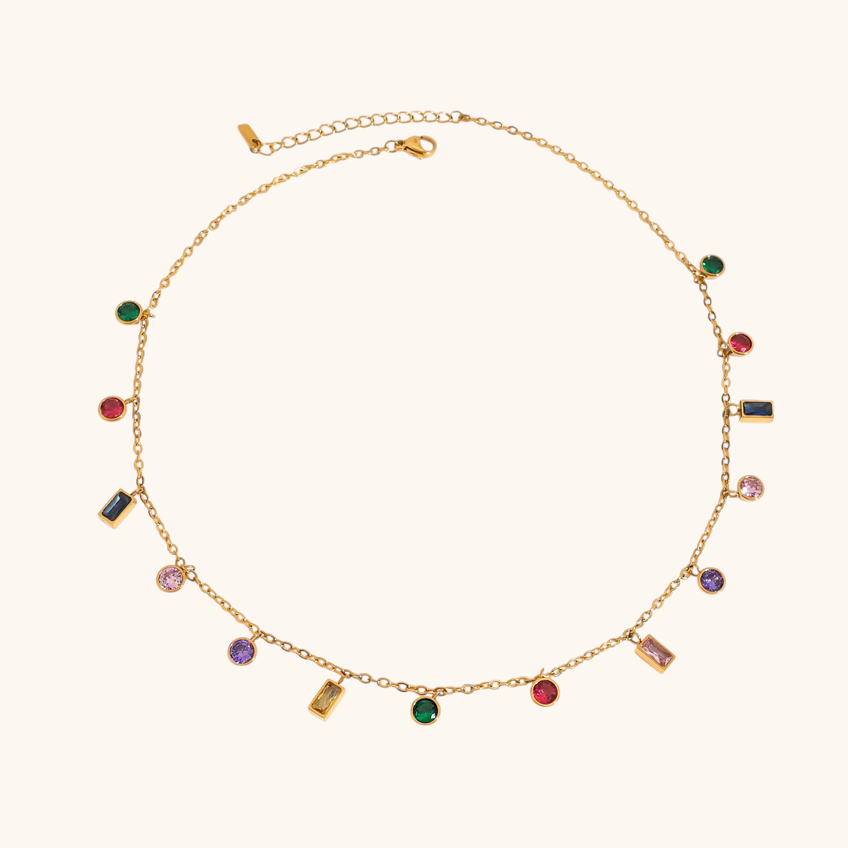 Vibrant multi-stone charm necklace laid flat, featuring pink, green, purple, and black stones on gold chain