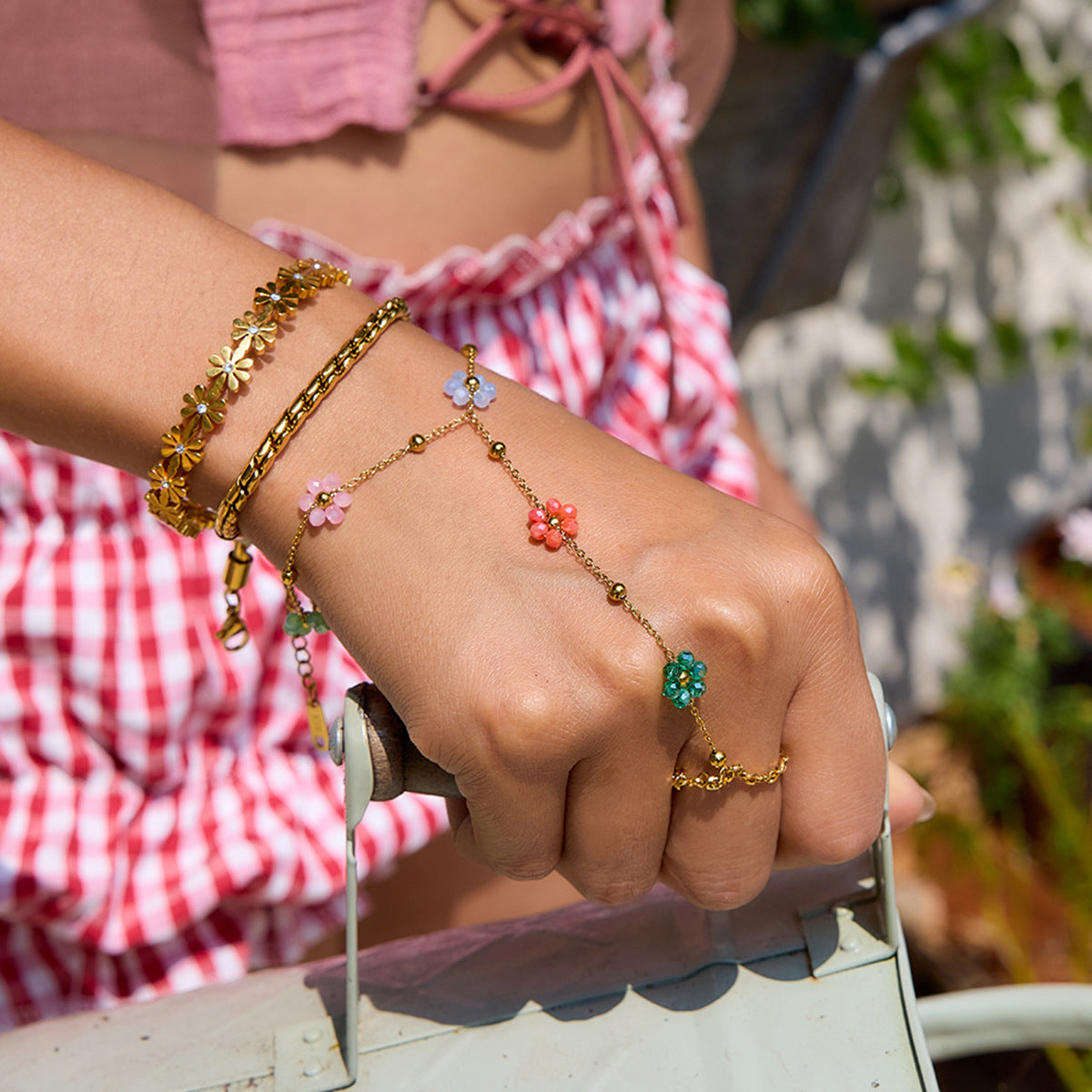 Close-up of multi-flower hand chain with gold beads and colorful daisy details