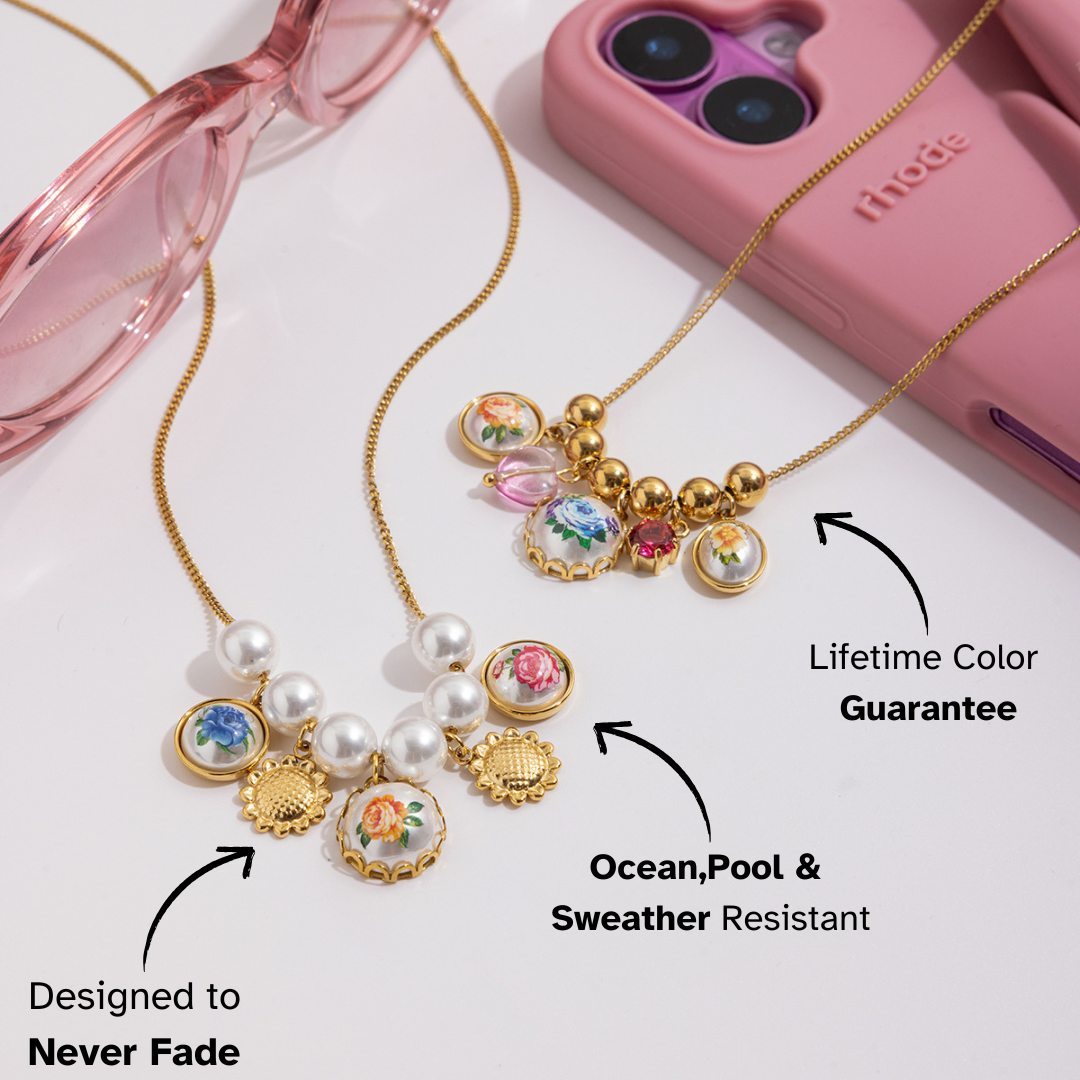 Necklace with floral and pearl details on a white background with pink sunglasses and phone case.