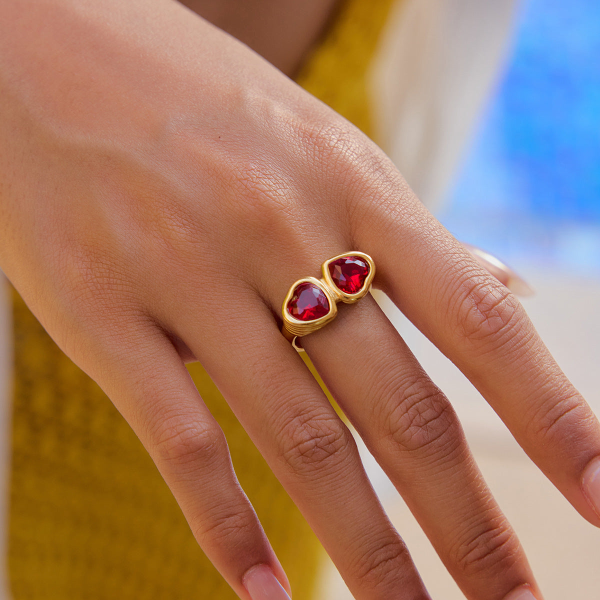 Romantic red heart gemstone ring worn by woman near poolside in summer light