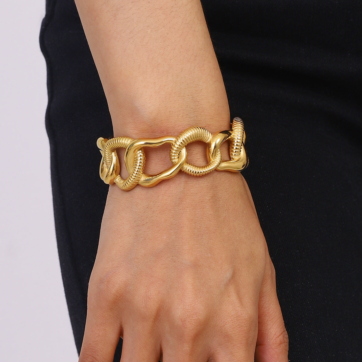 Model wearing bold gold chain bracelet with black outfit