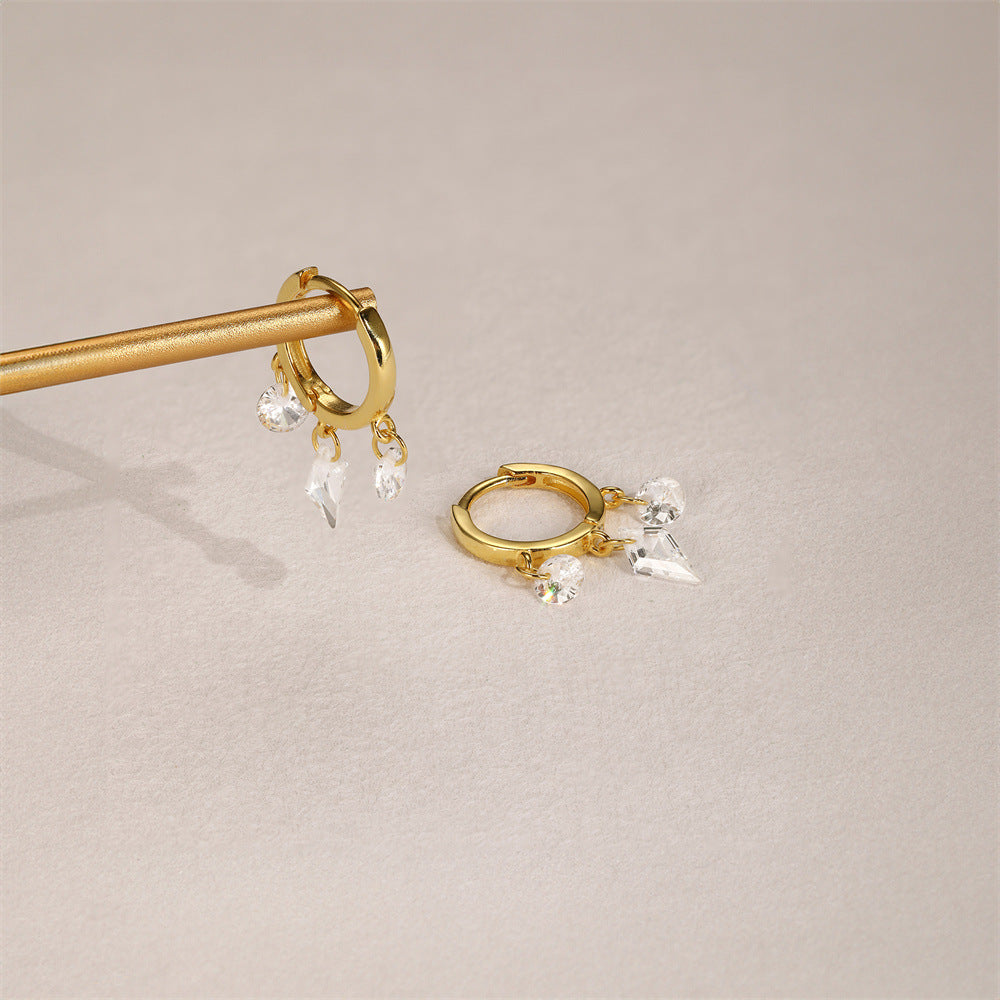 Lifestyle photo of dangling gold hoops with round and cone-shaped crystals