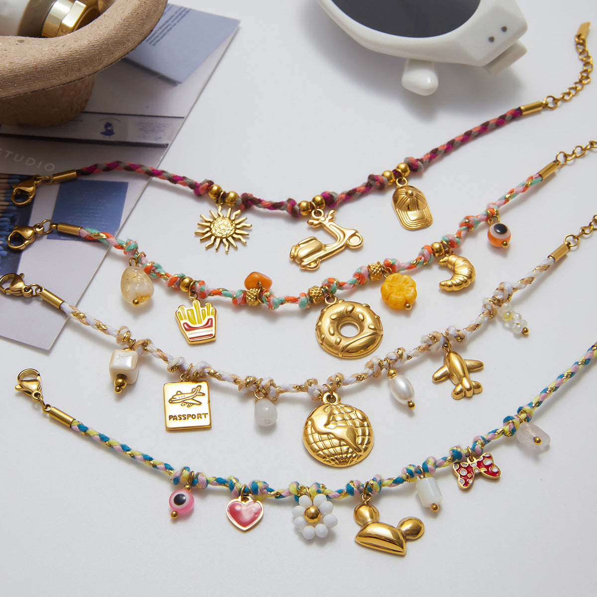 Flat lay of braided travel-themed bracelet with globe and passport charms