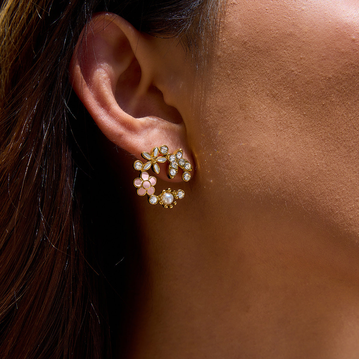 Close-up of an ear wearing a decorative earring with pink gemstones.