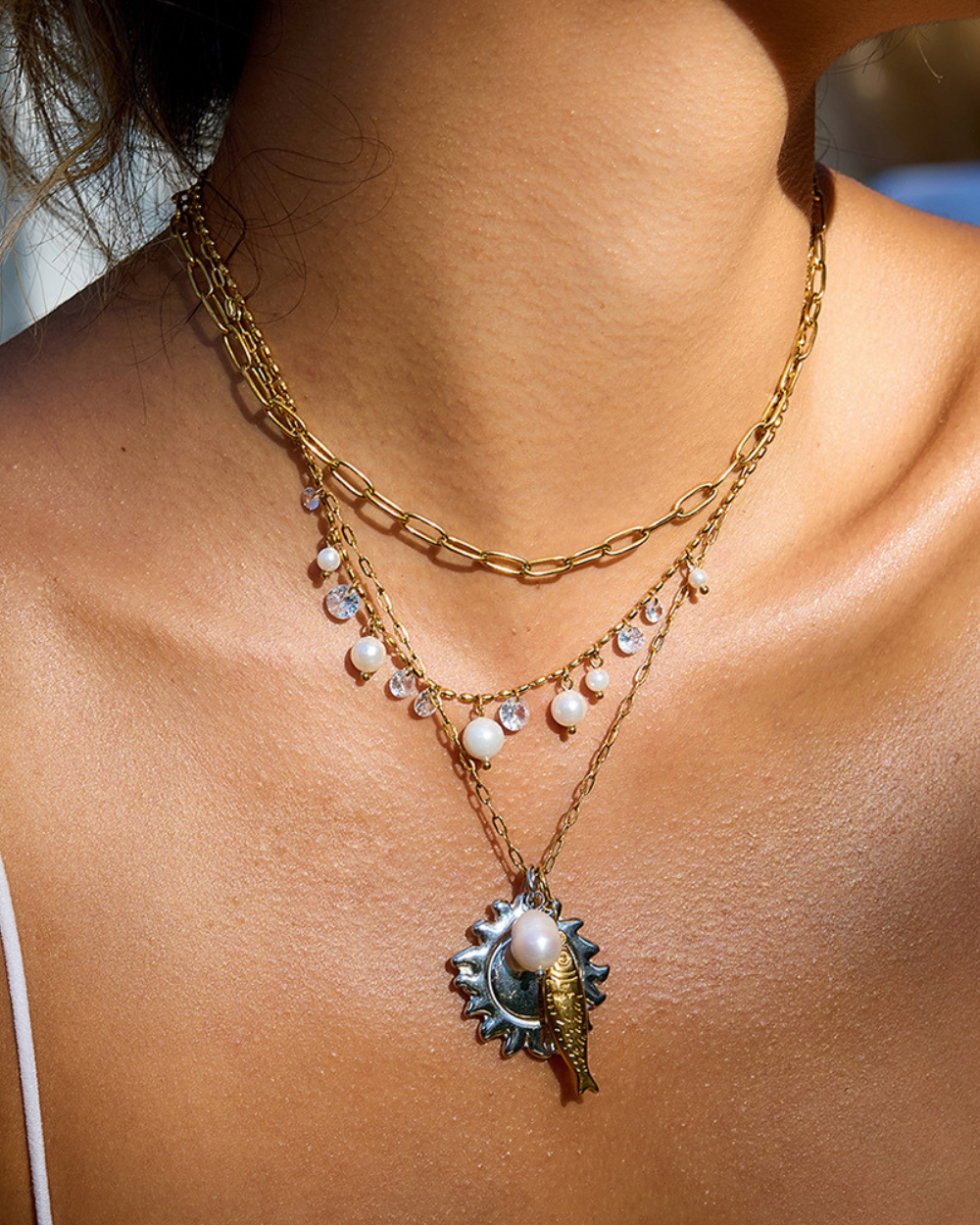 Necklace with a sun and moon pendant on a person's neck