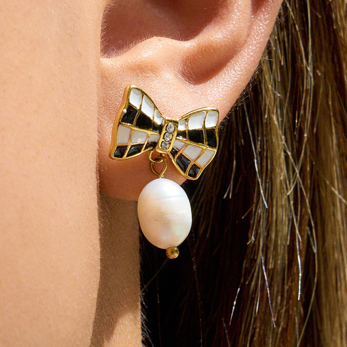 Earring with bow design and pearl drop worn on an ear