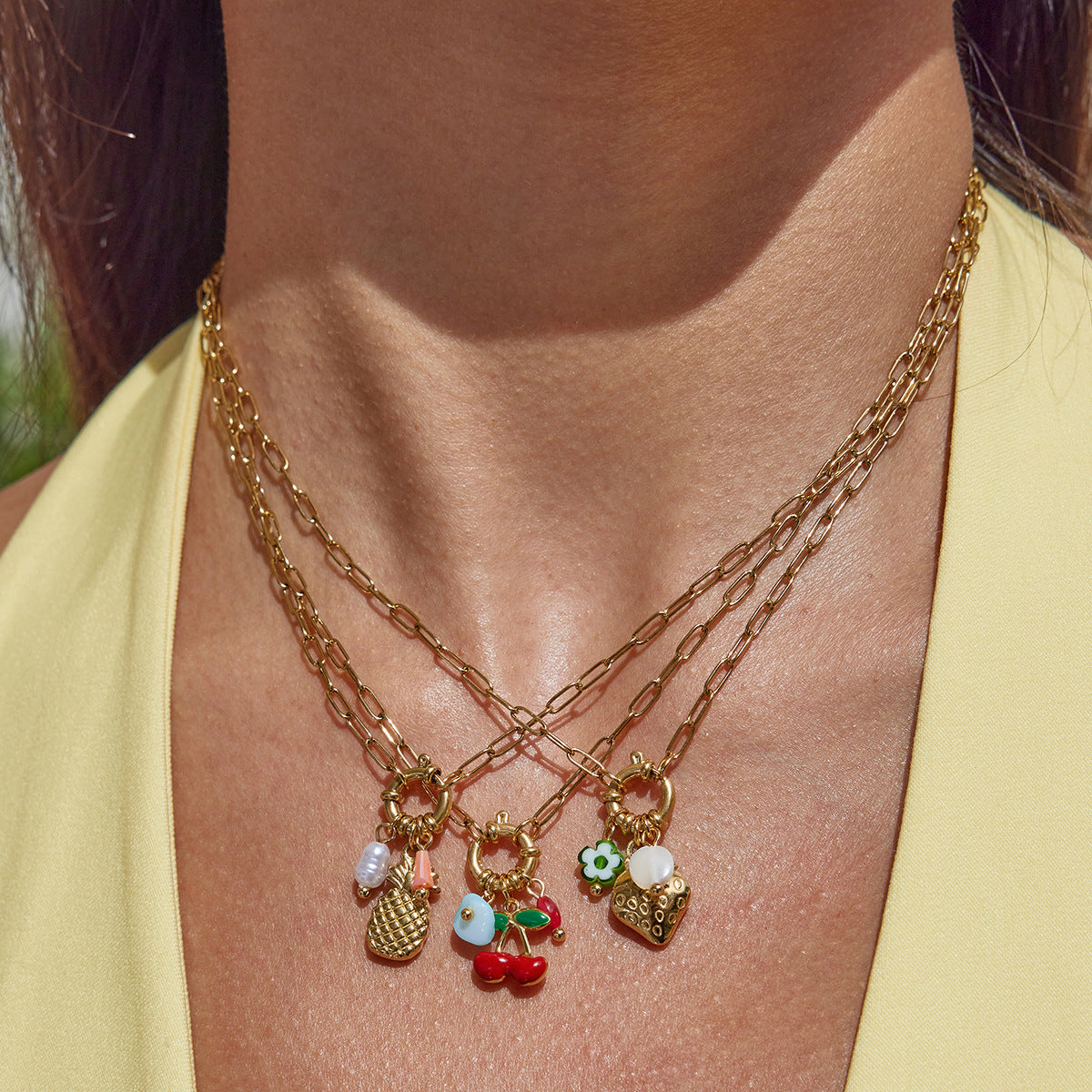 Gold necklaces with charms on a person wearing a yellow top.