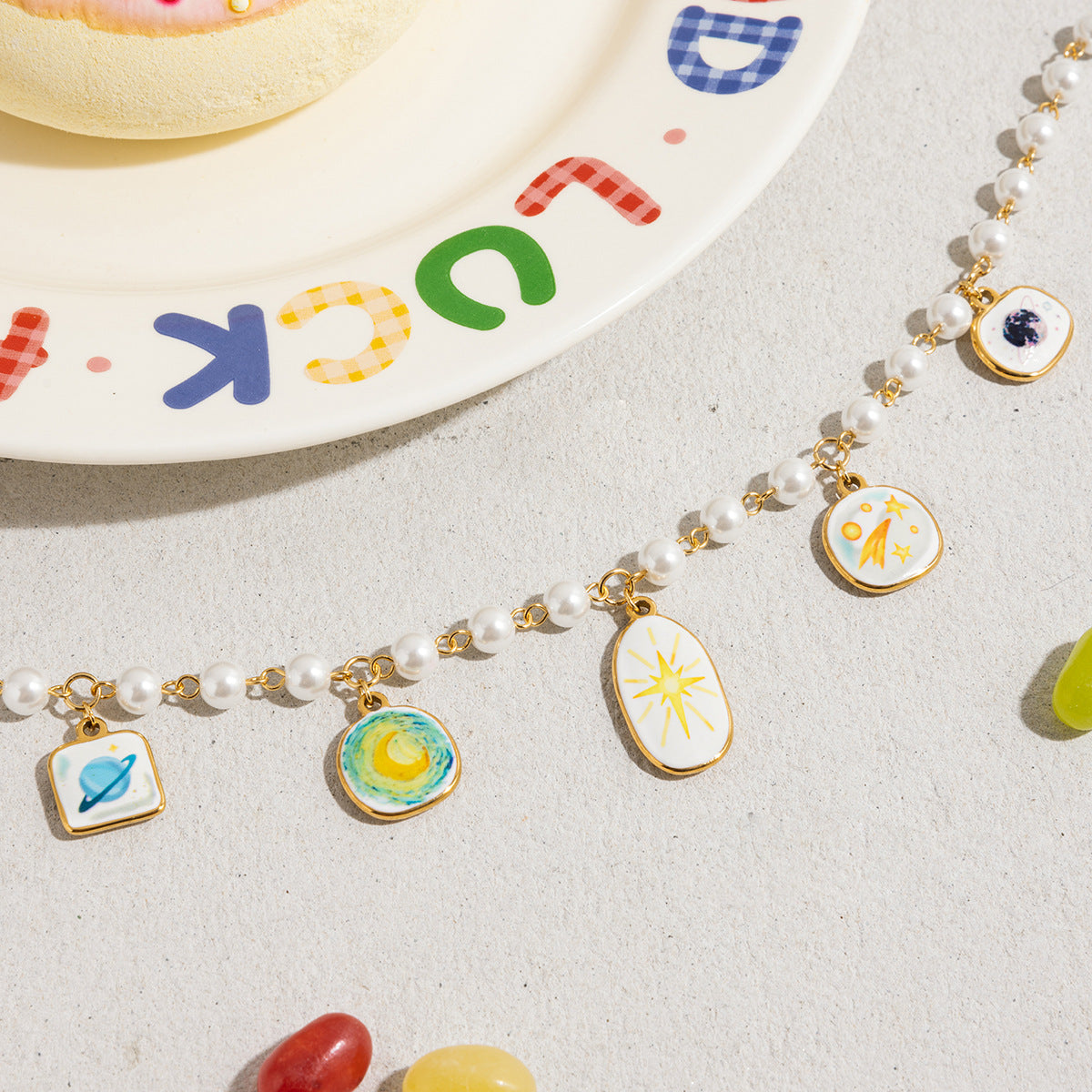 Cute celestial charm necklace laid out beside colorful plate and candy
