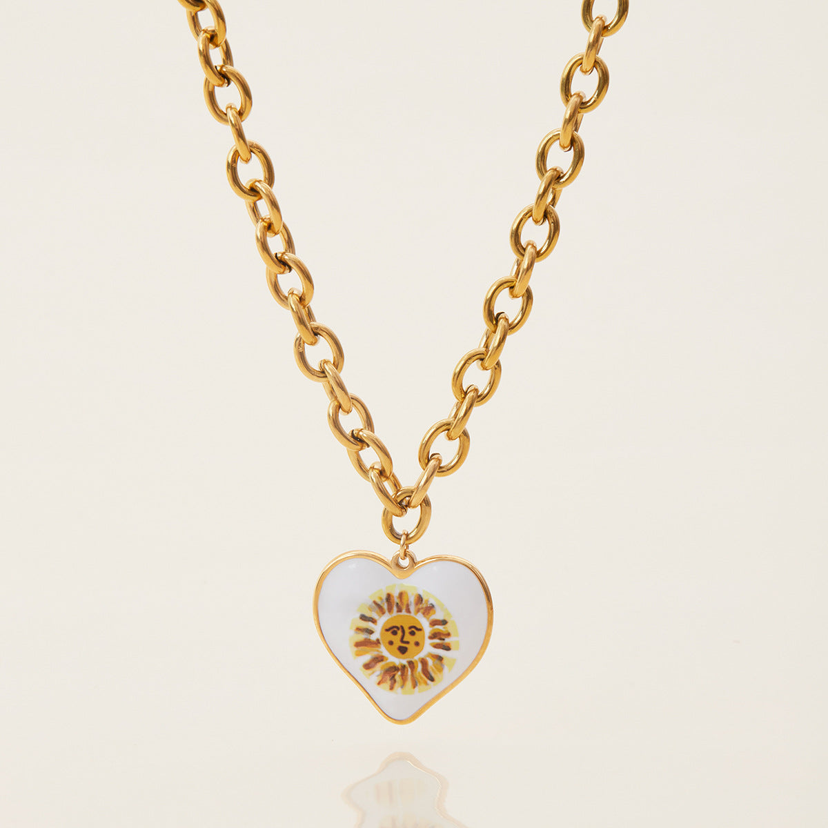 Studio flat lay of enamel sun face heart charm necklace with thick chain