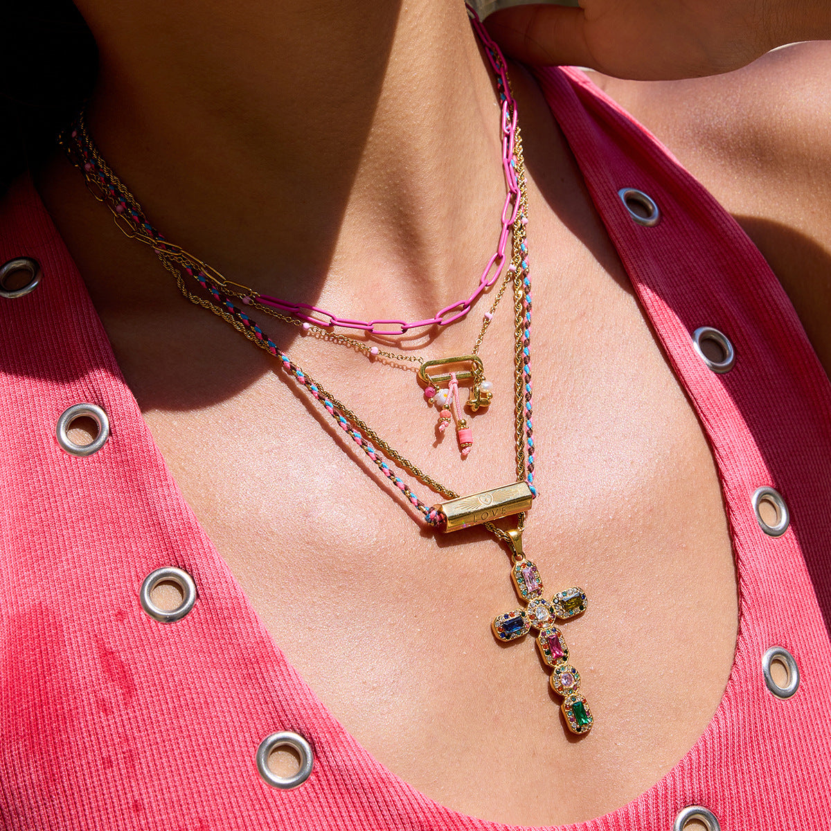 Model wearing layered necklaces with LOVE engraved pendant and pink top
