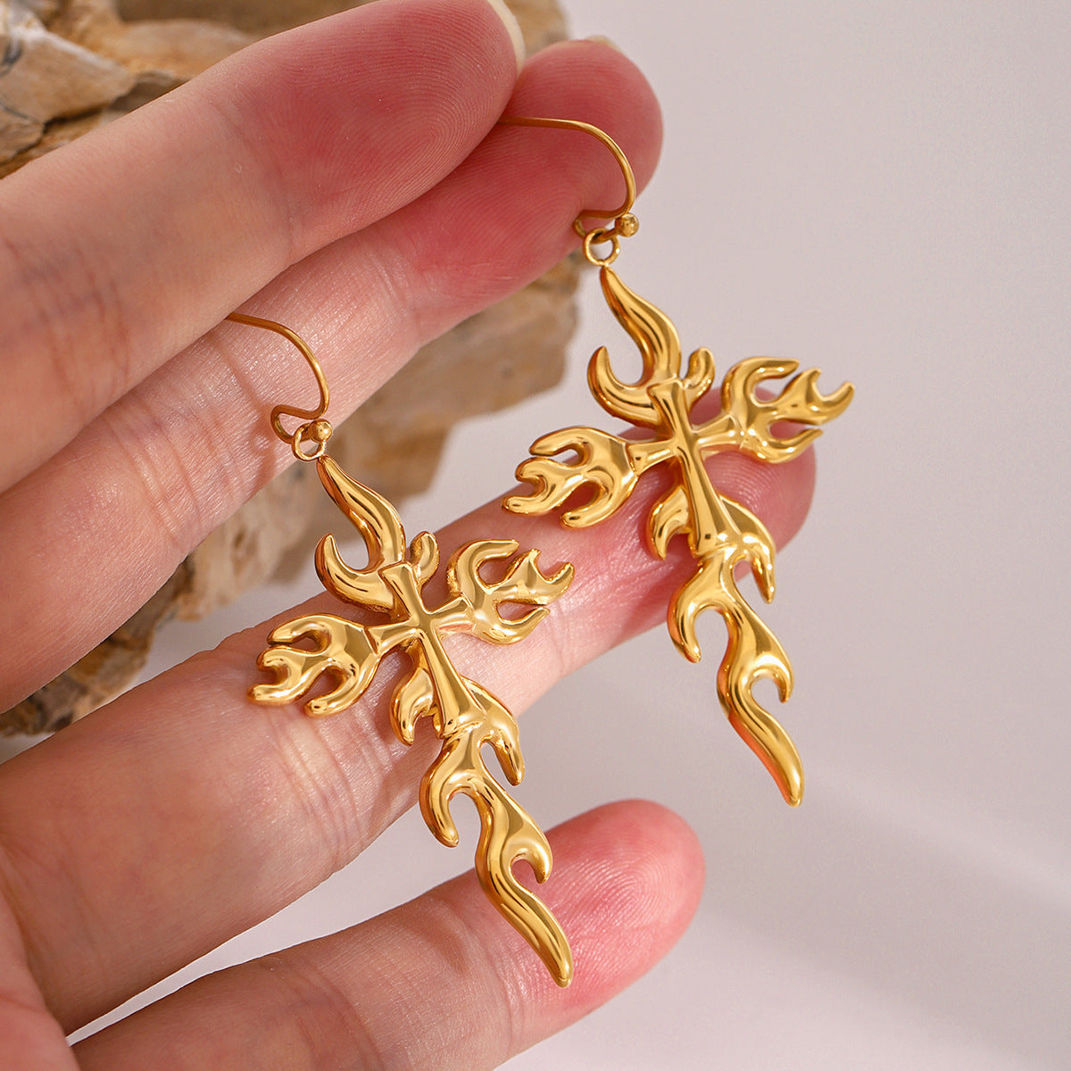 Y2K-inspired gold flame earrings displayed on stone surface