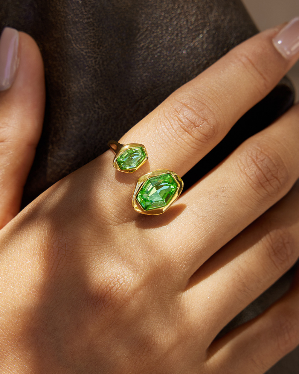 Gold rings with green gemstones on a hand