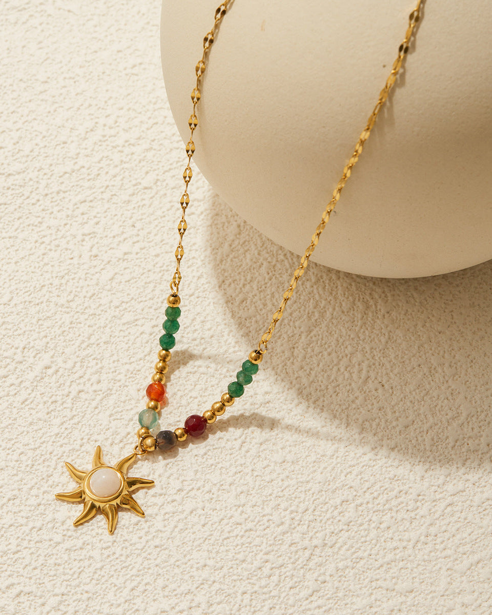 Necklace with sun pendant and multicolored beads on a textured beige background