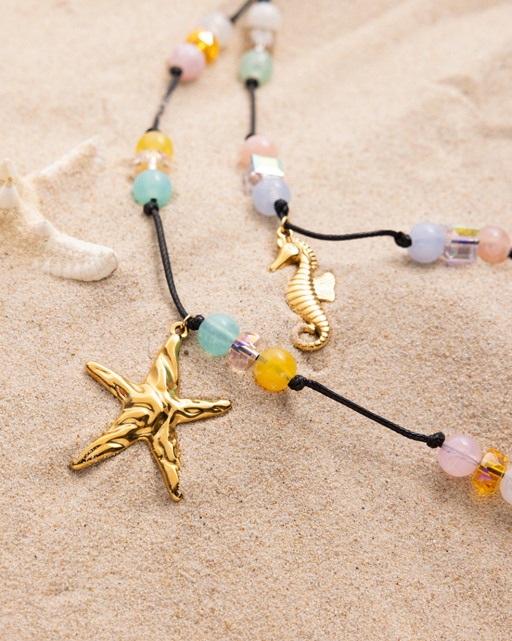 Necklace with starfish and seahorse pendants on a sandy background