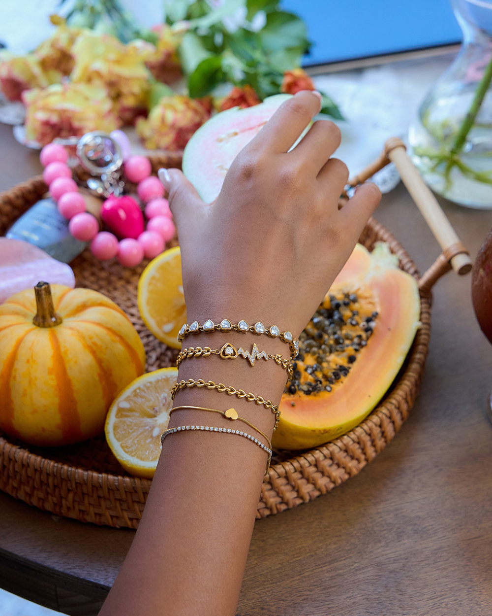 Hand with bracelets on a tray of fruits and a colorful bracelet in the background