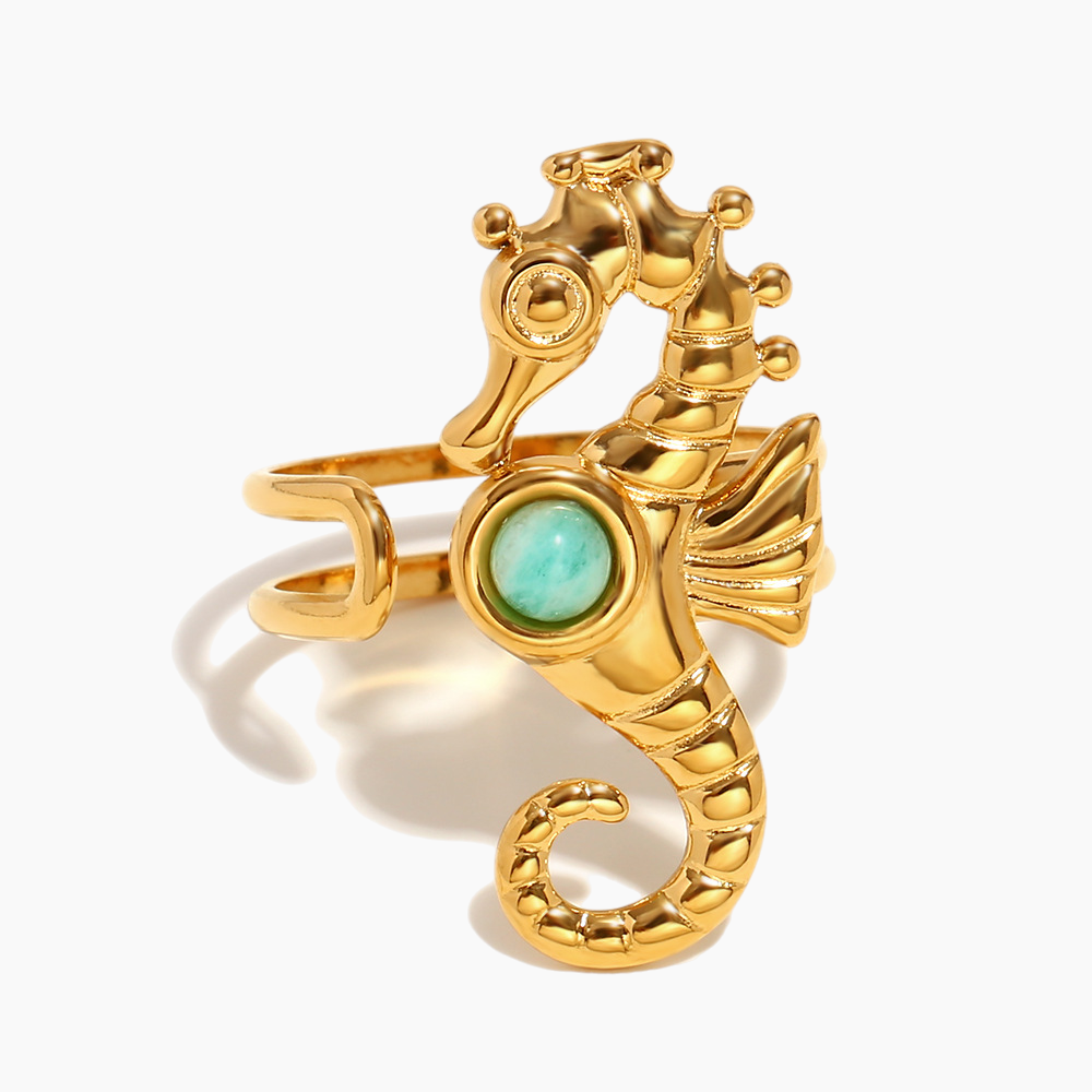 Gold seahorse-shaped ring with a green gemstone on a white background