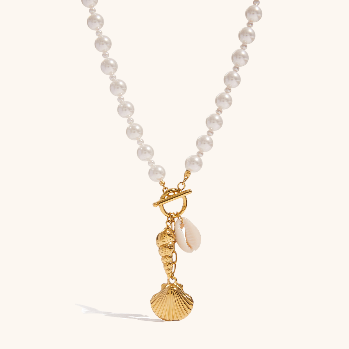 Product image of gold toggle necklace with pearl beads and ocean charms on a plain background