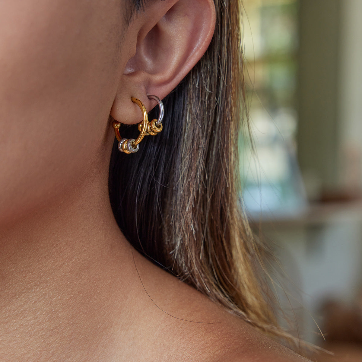 Model wearing two-tone gold and silver hoop earrings