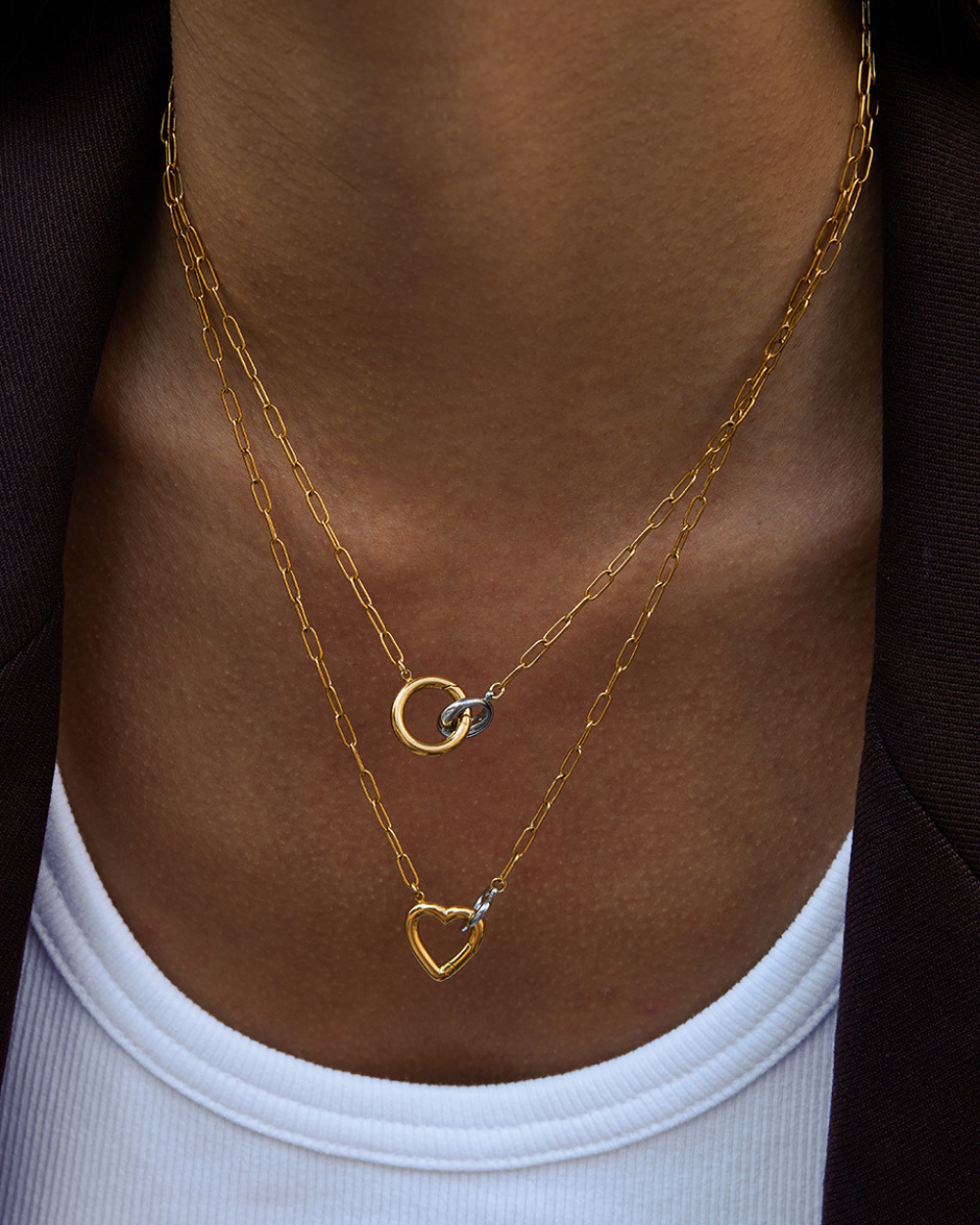 Gold necklaces with heart and moon designs on a person's neck.