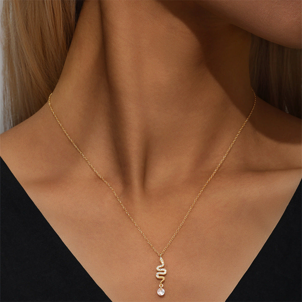 Model wearing dainty gold snake necklace with a sparkle pendant, styled with black outfit